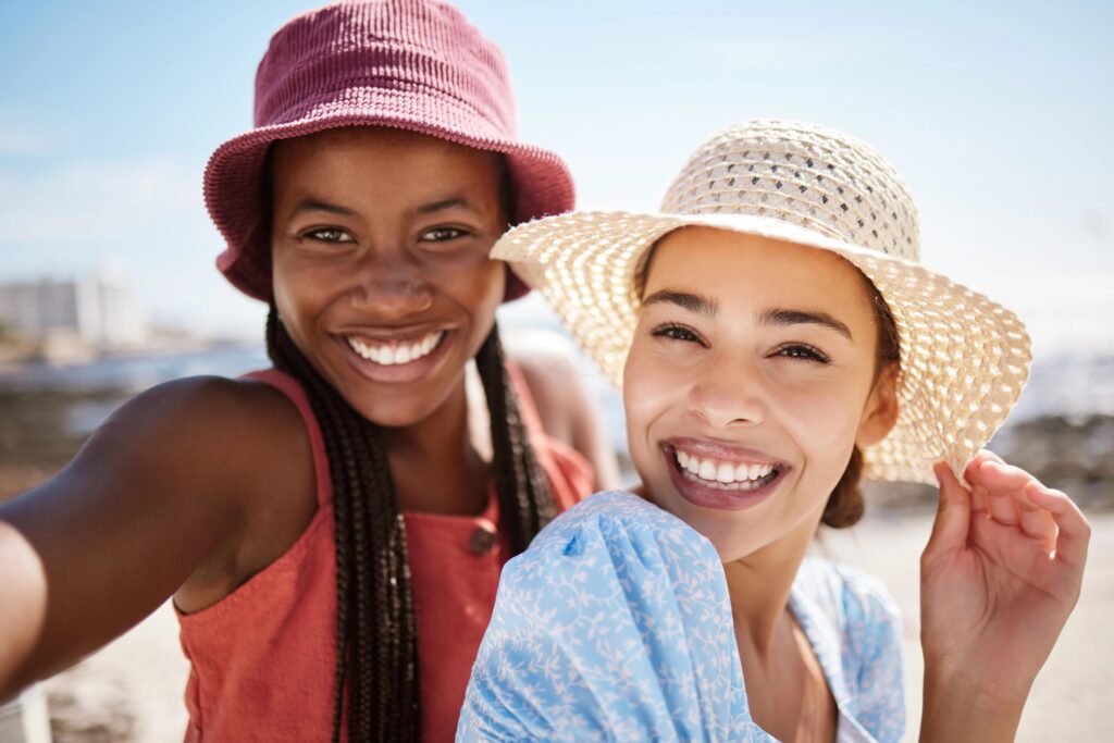 A smiling woman and girl enjoying a sunny day at the beach.