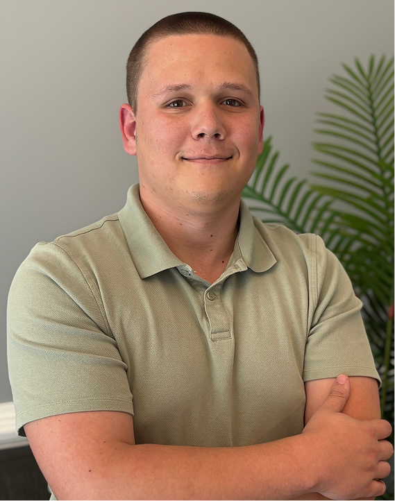 Young man in a light green polo shirt smiling confidently indoors.