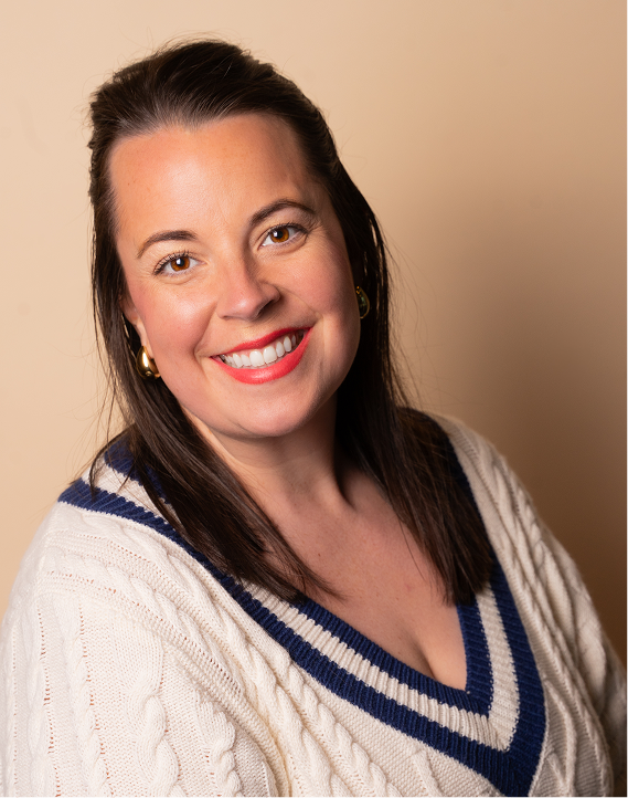 Smiling woman with dark hair and a white sweater with blue stripes.