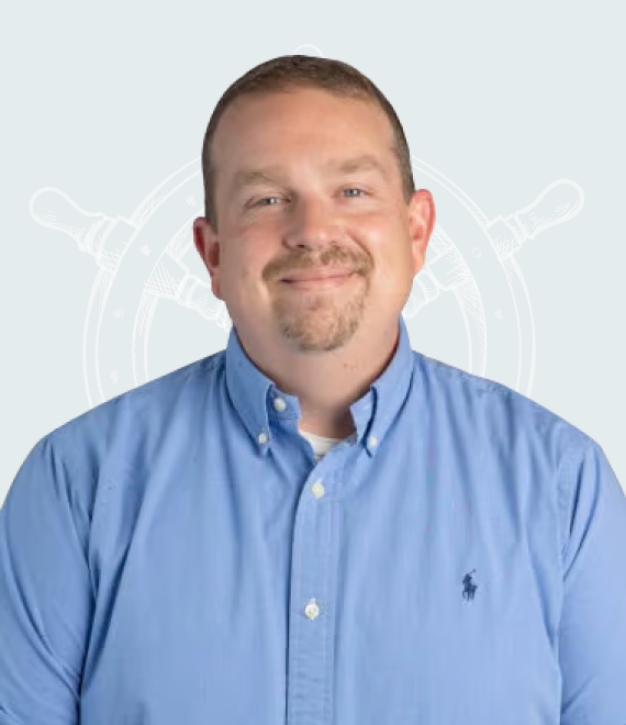 Professional headshot of a man with short hair and a goatee wearing a light blue Ralph Lauren button-down shirt, smiling against a soft pink background with a subtle decorative illustration.