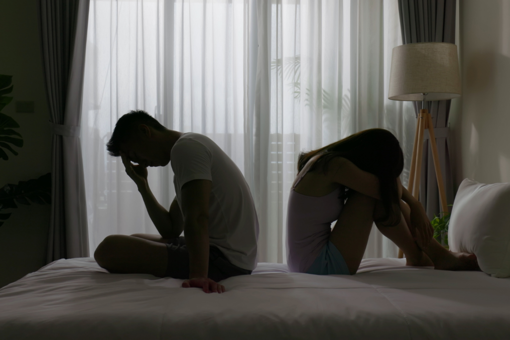 Couple experiencing emotional distress in a bedroom setting.