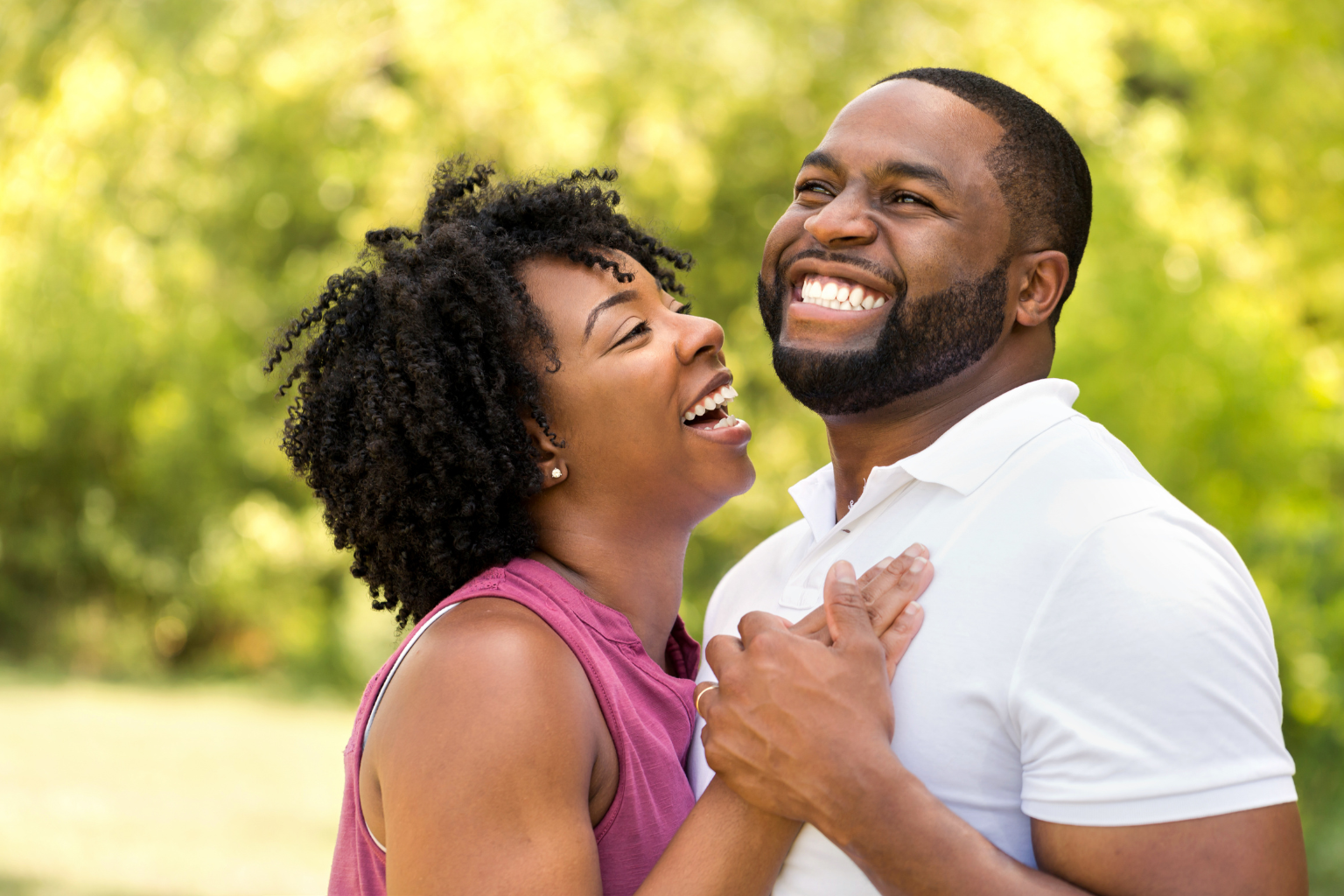 Happy couple enjoying outdoor moment in park with lush green background.