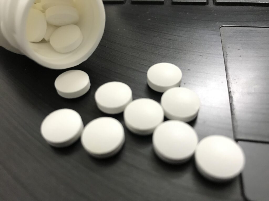 White pills spilled from a bottle on a dark surface at Inner Voyage Recovery Center.