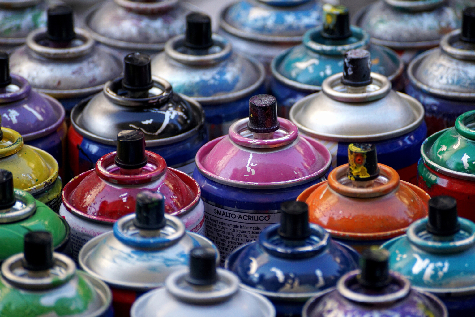 Colorful spray paint cans arranged in a row for artistic projects.