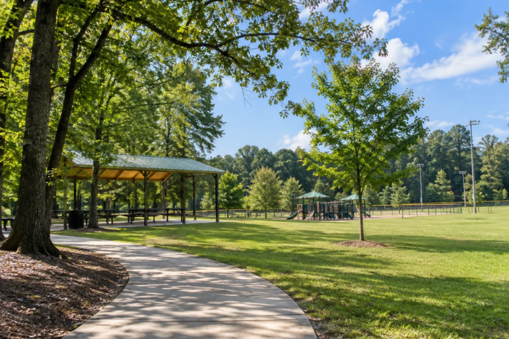Park with shaded walkway and picnic shelters at a sunny day.